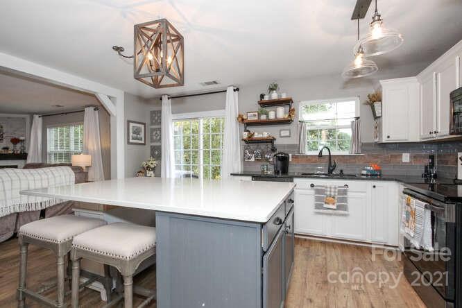 1431 River Run Road Lowell, NC 28098 - Photo 12 of 26 a kitchen with stainless steel appliances granite countertop a stove top oven a sink a dining table and chairs with wooden floor