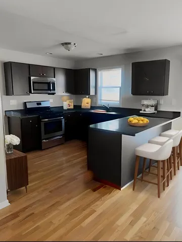 a kitchen with kitchen island granite countertop a stove a sink a counter top space and cabinets