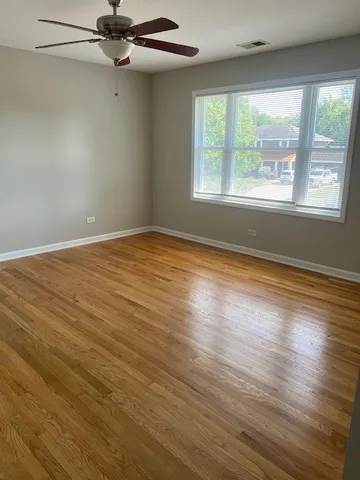 an empty room with wooden floor fan and windows