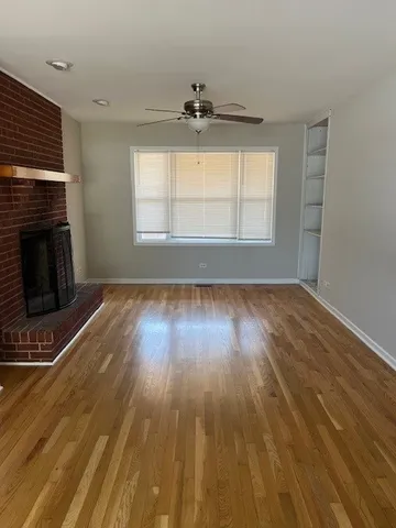 an empty room with wooden floor fireplace and windows