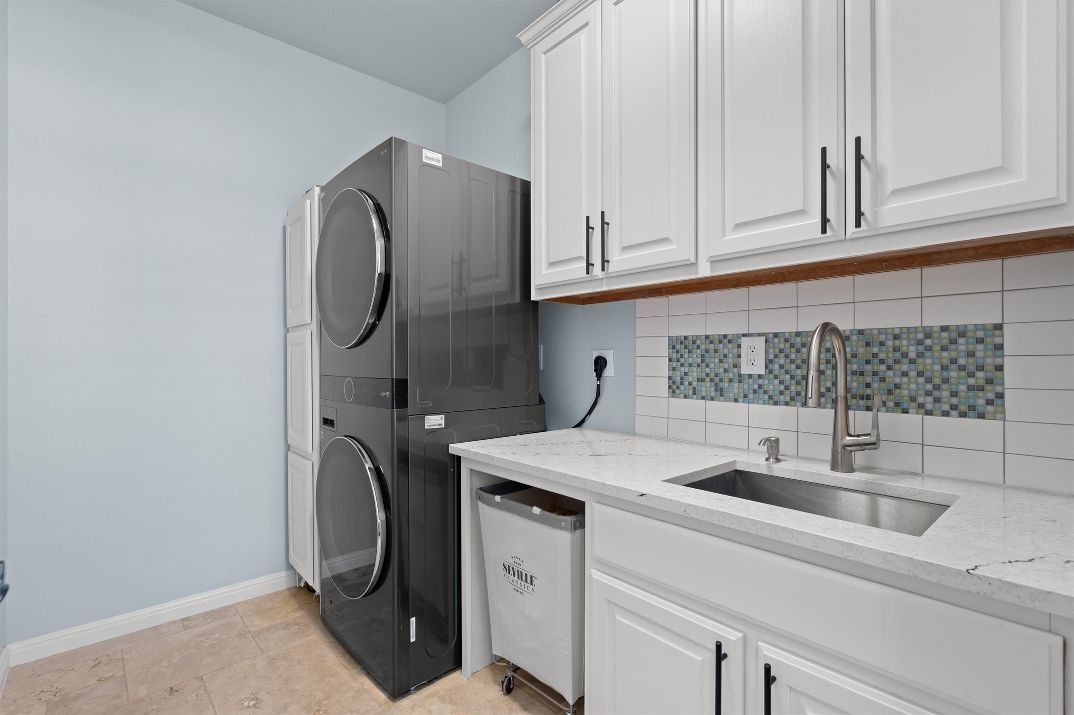 3105 Castellano Way Cedar Park, TX 78613 - Photo 26 of 40 functional first floor laundry room featuring built in cabinet, quartz countertop with utility sink, and space for full-size washer and dryer-designed for efficiently and organization.