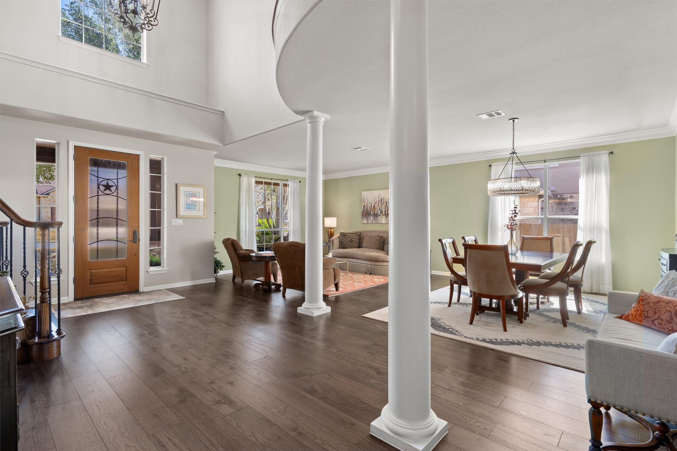 3105 Castellano Way Cedar Park, TX 78613 - Photo 4 of 40 Light-filled open foyer with soaring ceilings, rich wood newer flooring, and elegant architectural columns seamlessly connects formal living and dining spaces-ideal for living and entertaining.