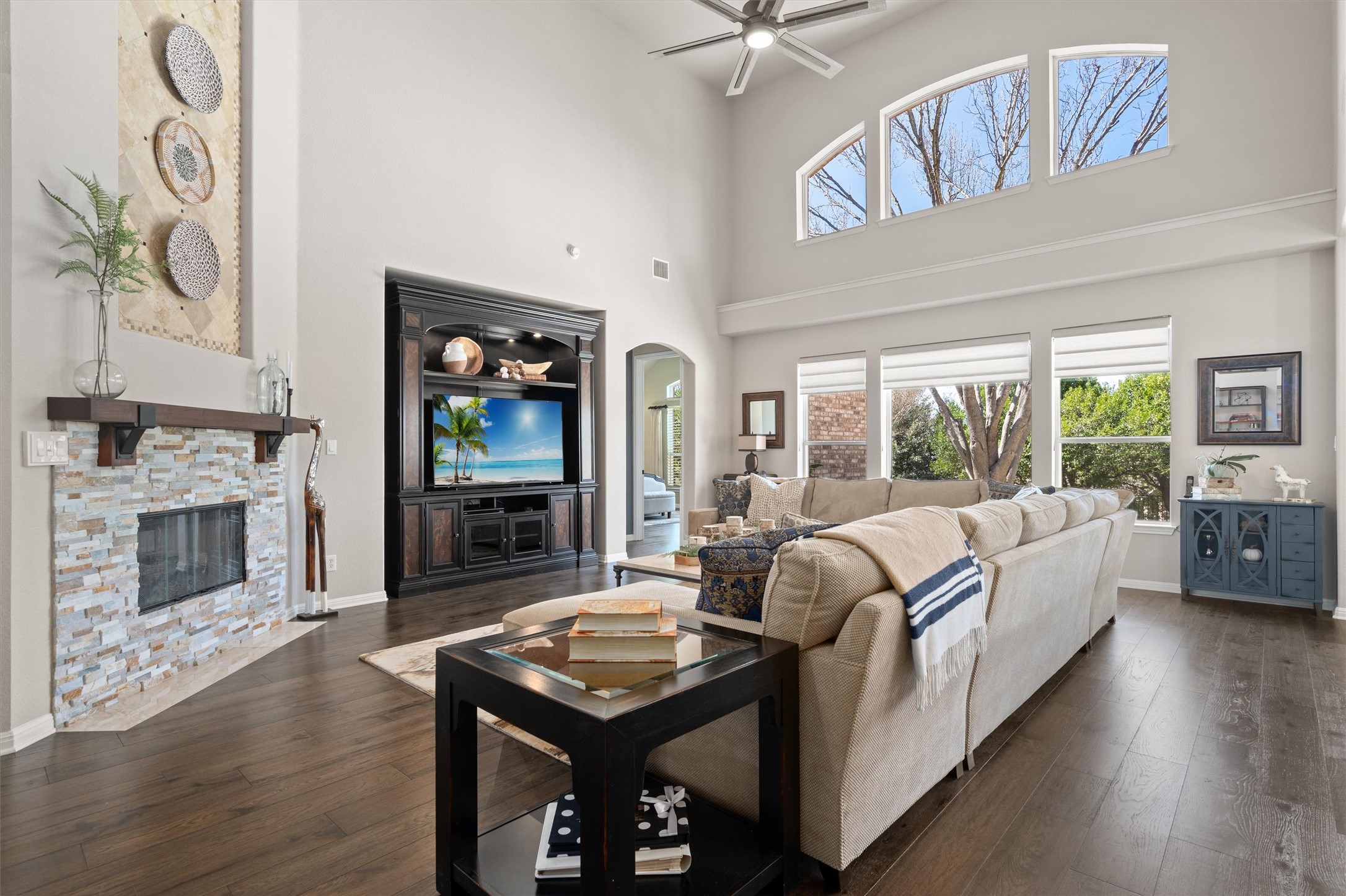 3105 Castellano Way Cedar Park, TX 78613 - Photo 8 of 40 Expansive family room featuring soaring ceilings, a wall of windows for abundant natural light, and a cozy fireplace complemented by recently upgraded deep-toned wood flooring though out.