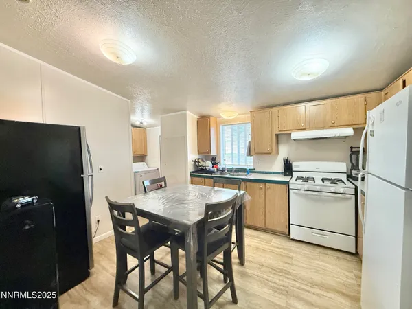 a kitchen with a refrigerator a stove a sink and white cabinets with wooden floor