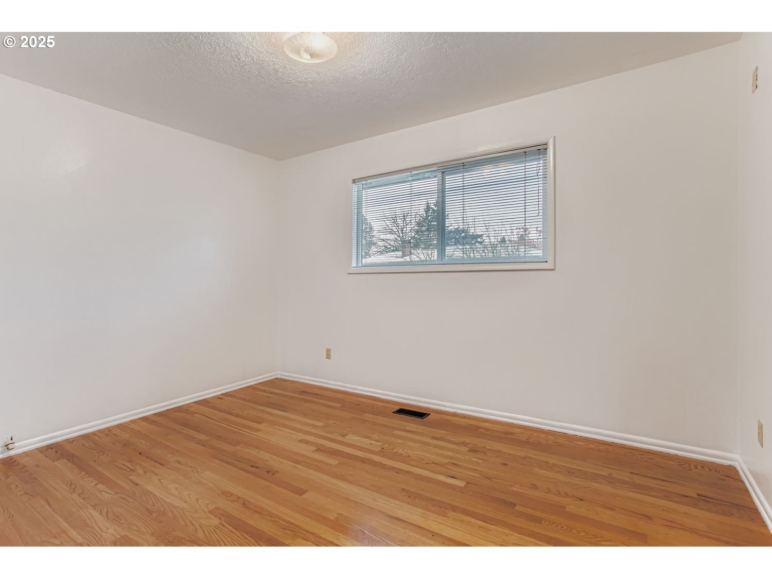 10832 Southeast Stephens Street Portland, OR 97216 - Photo 13 of 36 an empty room with wooden floor and windows
