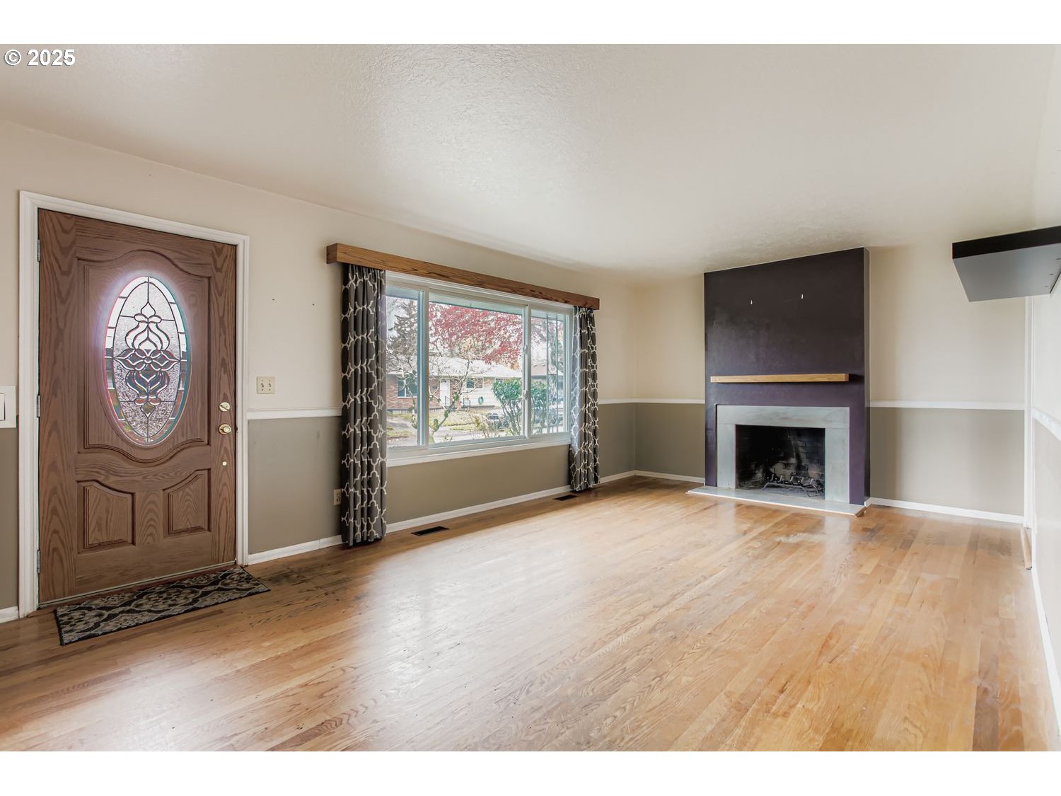 10832 Southeast Stephens Street Portland, OR 97216 - Photo 5 of 36 a view of an empty room with a fireplace and wooden floor