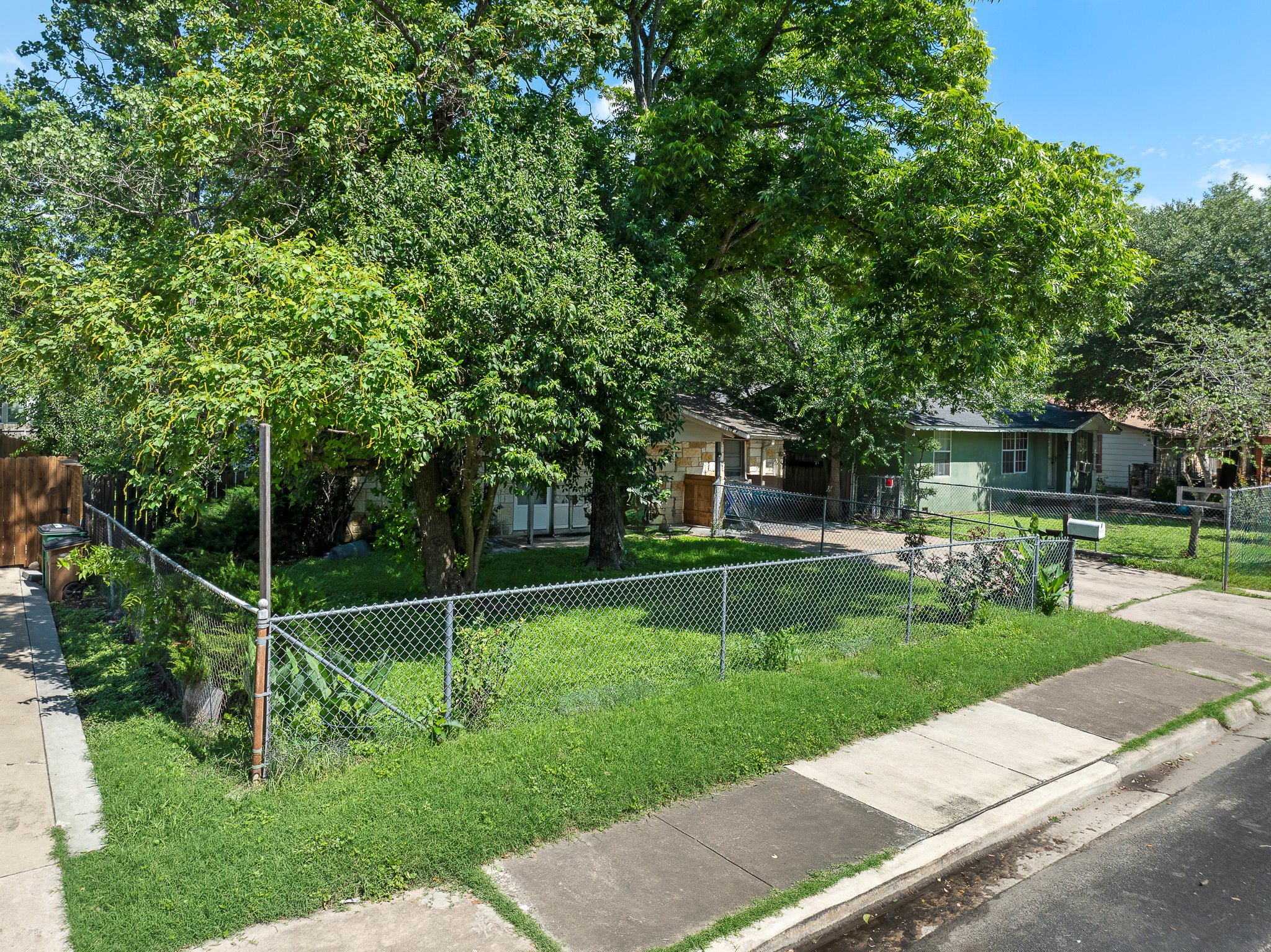 1122 Spur Street, Unit D Austin, TX 78721 - Photo 2 of 6 Fenced front yard with mature trees and a chain-link perimeter