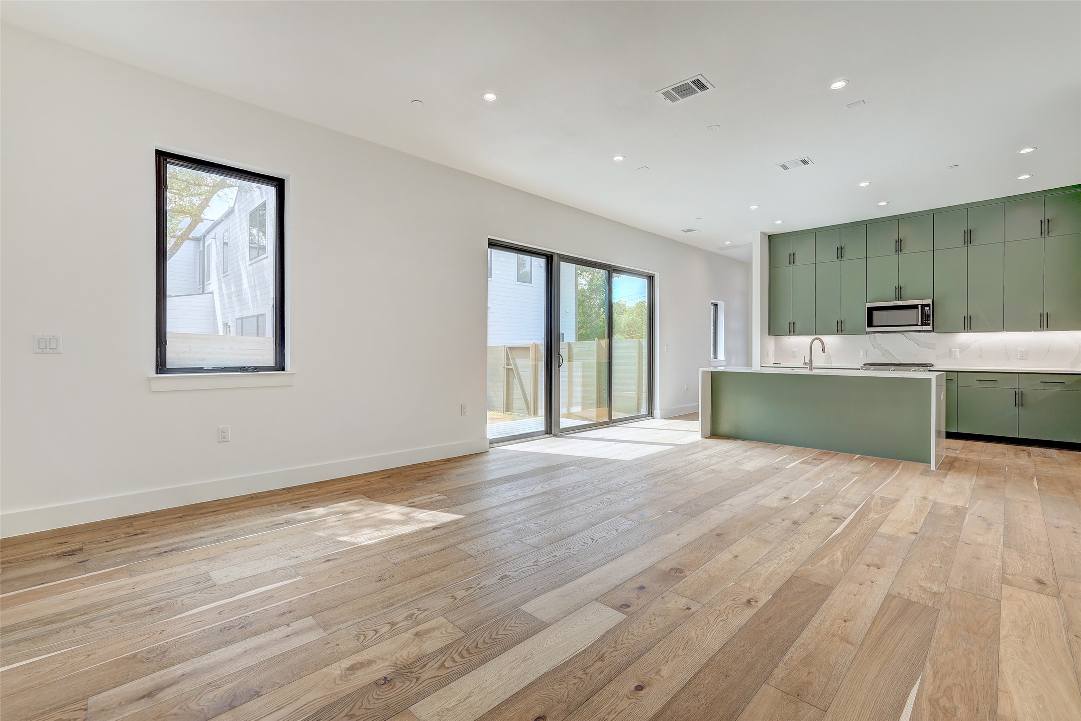 3208 Clawson Road, Unit 5A Austin, TX 78704 - Photo 33 of 34 Kitchen with green cabinets, light wood-type flooring, light countertops, stainless steel microwave, and open floor plan