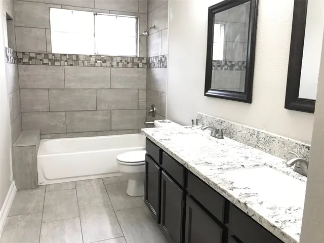 a bathroom with a granite countertop sink a toilet and bathtub
