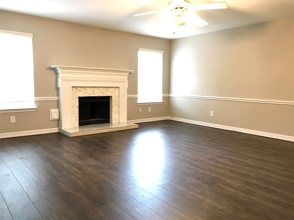 5722 Fort Sumter Lane Houston, TX 77084 - Photo 2 of 22 an empty room with wooden floor fireplace and windows