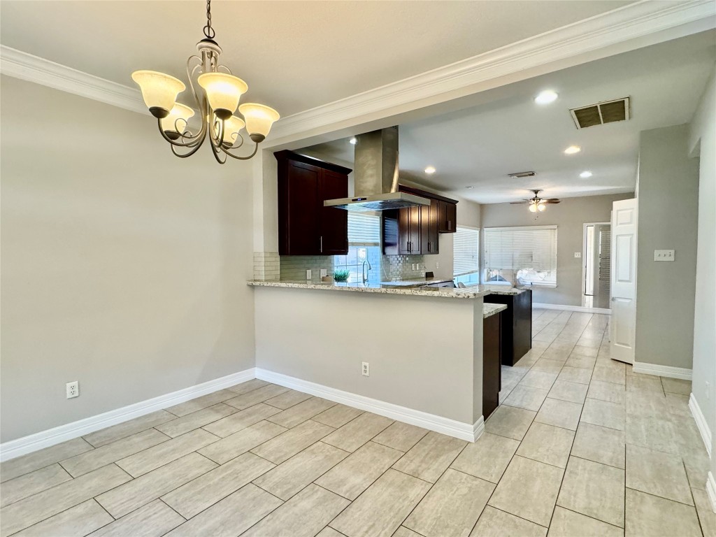 5722 Fort Sumter Lane Houston, TX 77084 - Photo 6 of 22 a room with kitchen island stainless steel appliances a chandelier and fireplace
