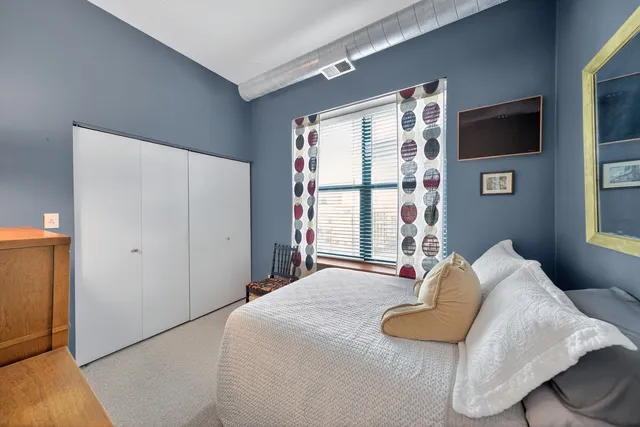 a bedroom with a bed and a lamp on the dresser