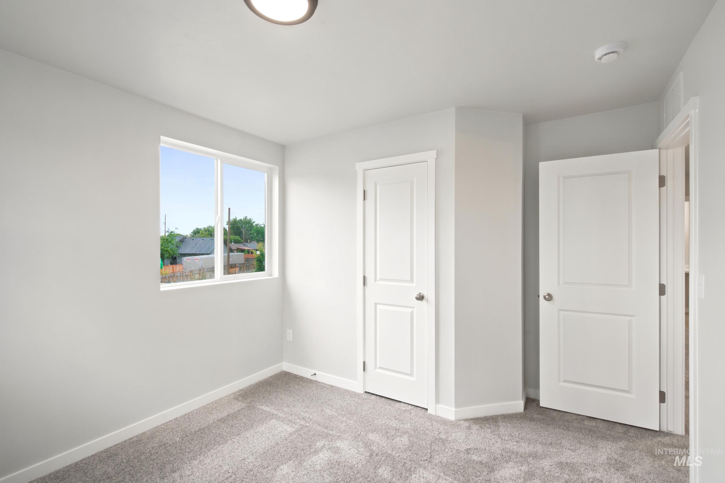 472 Merlin Court Middleton, ID 83644 - Photo 18 of 25 Light gray walls with white trim, gray patterned carpet, white interior doors, and a flush mount ceiling light