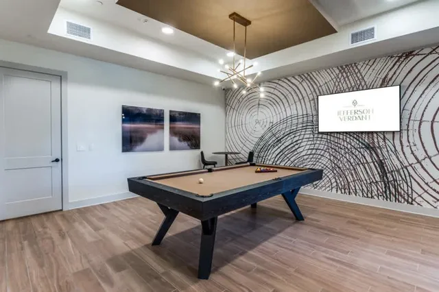 a room with wooden floor pool table and flat screen tv