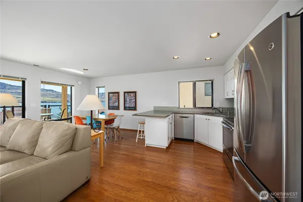 a living room with stainless steel appliances furniture and a kitchen view