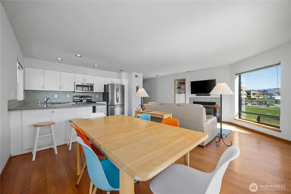 a kitchen with stainless steel appliances kitchen island a table chairs in it and wooden floors