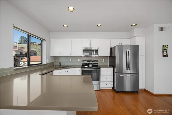 a kitchen with stainless steel appliances granite countertop a refrigerator a stove and a sink