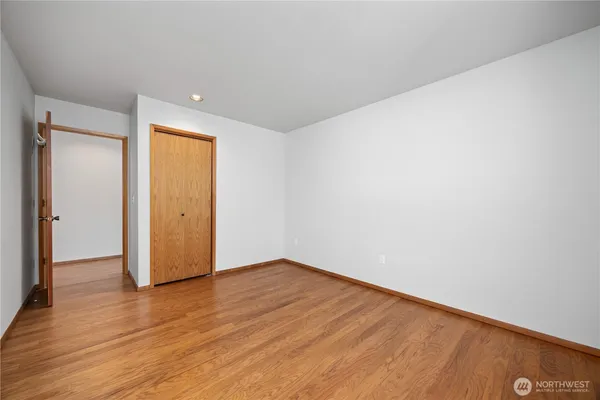 a view of an empty room with wooden floor and closet