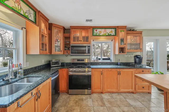 a large kitchen with stainless steel appliances granite countertop a stove sink and cabinets