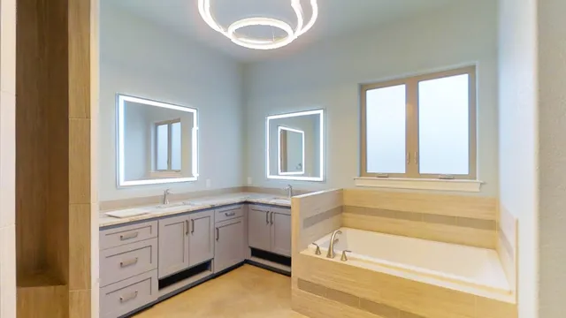a bathroom with a granite countertop sink and a bathtub next to a window