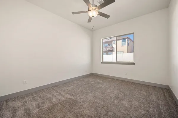 an empty room with a window and a fan