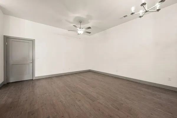 an empty room with wooden floor and fan