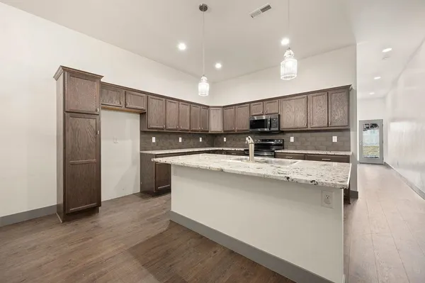 a kitchen with kitchen island granite countertop wooden cabinets and refrigerator