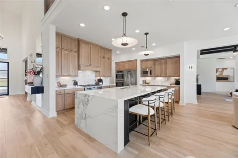 an open kitchen with wooden floor and stainless steel appliances
