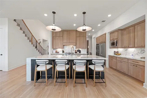 a kitchen with stainless steel appliances kitchen island granite countertop a dining table chairs and sink