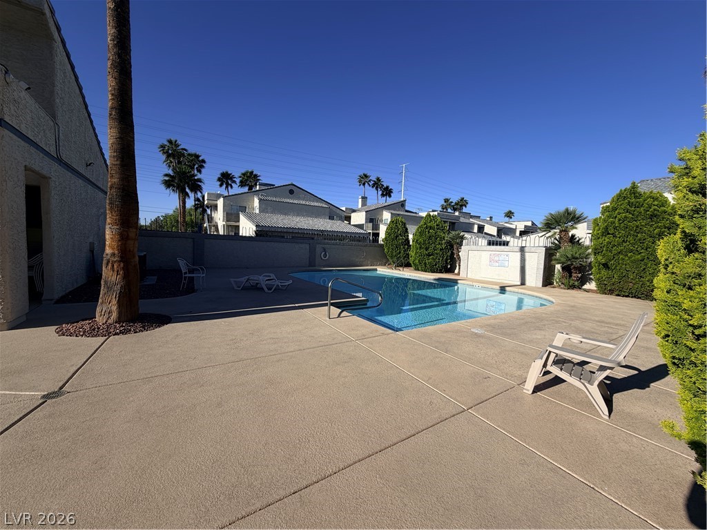 6250 West Flamingo Road, Unit 4 Las Vegas, NV 89103 - Photo 44 of 45 An inviting in-ground pool beckons under a clear blue sky, surrounded by lush landscaping.