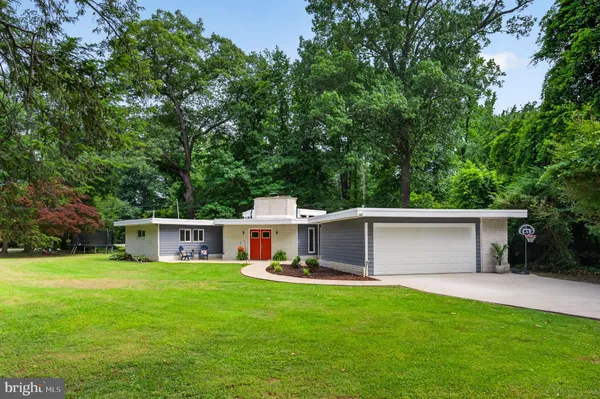 a view of a white house with a big yard and large trees