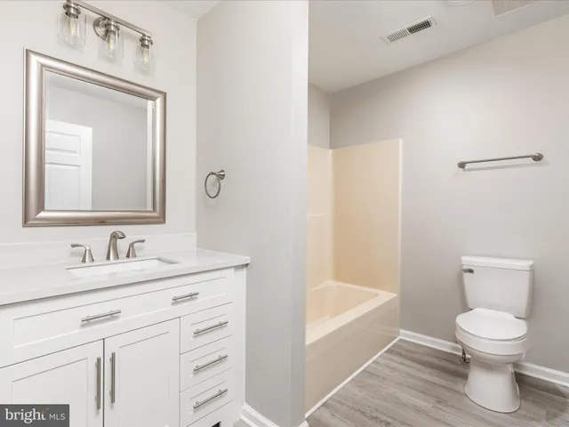 an empty room with wooden floor ceiling fan and windows