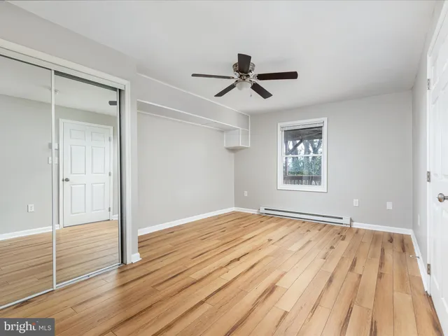 a view of empty room with wooden floor and ceiling fan
