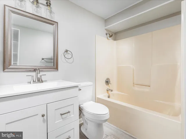 a bathroom with a bathtub shower sink mirror and toilet