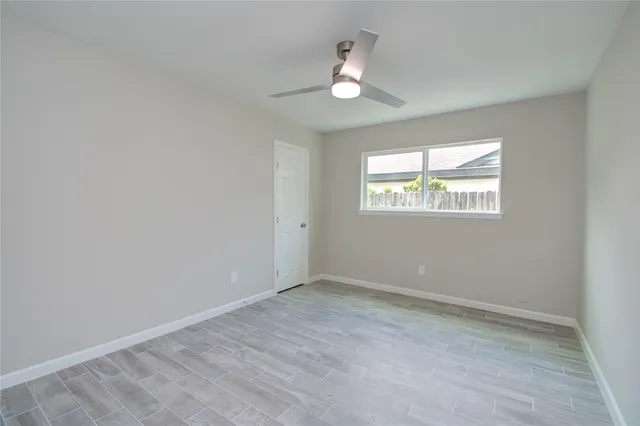 an empty room with windows and fan