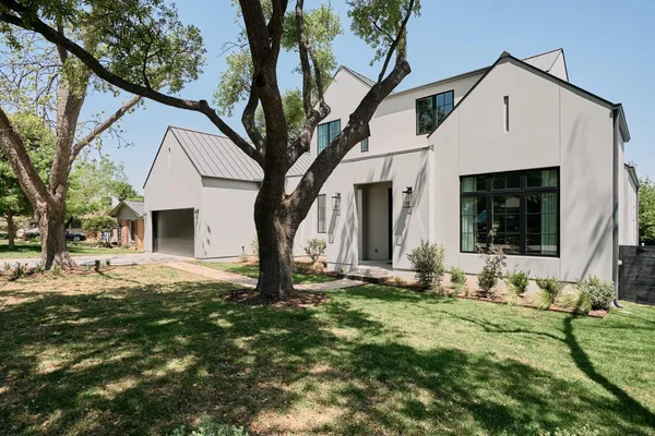a view of a yard in front of a house with large tree