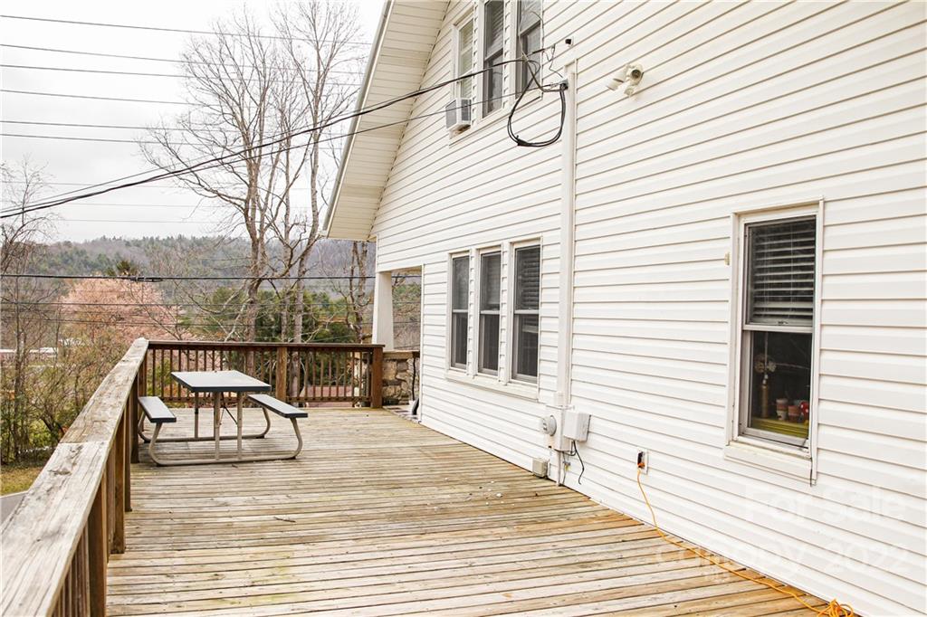 1052 Greenwood Road Spruce Pine, NC 28777 - Photo 6 of 43 a view of a roof deck with table and chairs a barbeque with wooden floor and fence