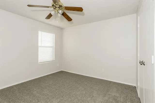 an empty room with a window and a fan