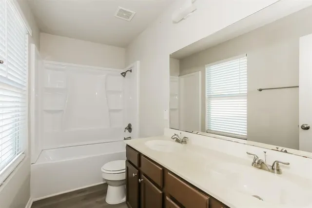 a bathroom with a double vanity sink toilet mirror and bathtub