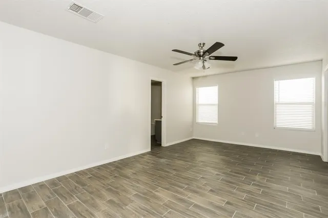 an empty room with windows and fan