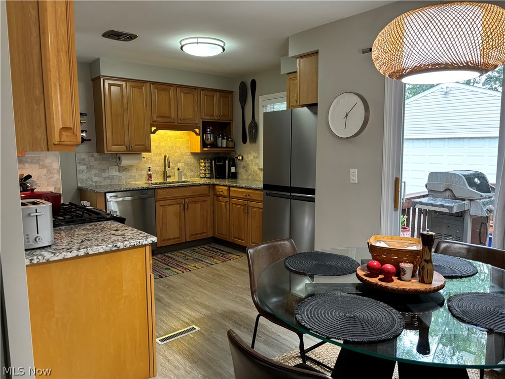 1440 West Miner Road Cleveland, OH 44124 - Photo 23 of 49 Kitchen featuring tasteful backsplash, light stone counters, appliances with stainless steel finishes, and a wealth of natural light