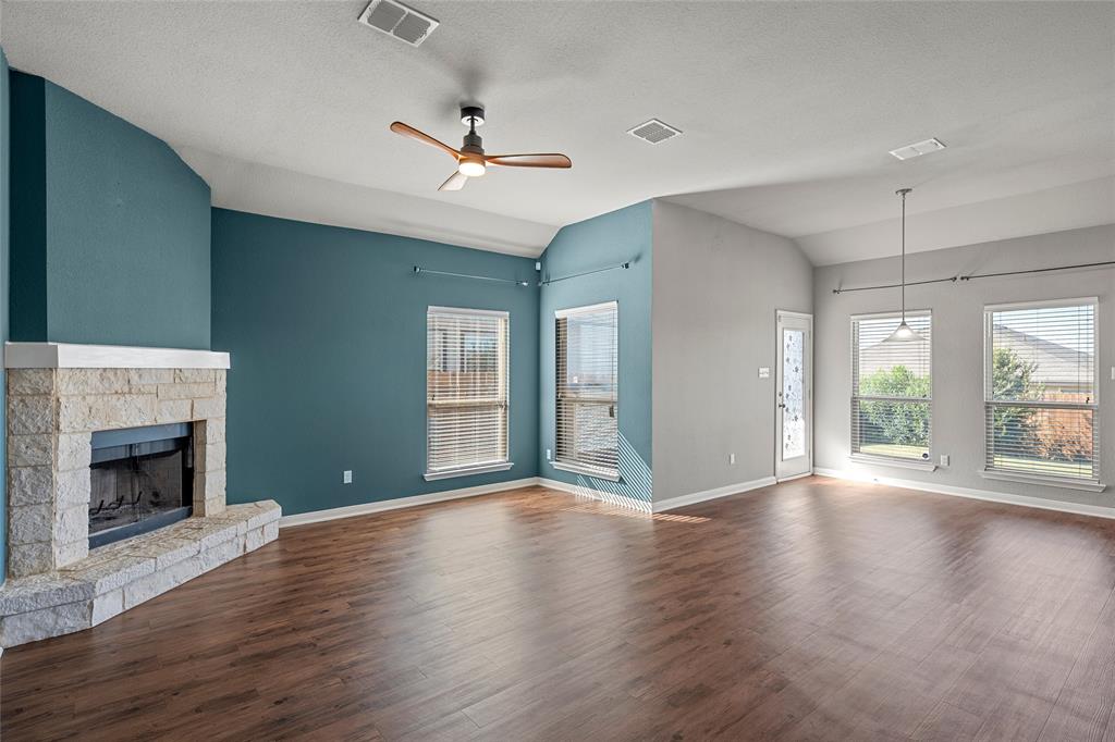 2813 Beutel Road Lorena, TX 76655 - Photo 1 of 1 Unfurnished living room featuring lofted ceiling, ceiling fan, dark wood-style flooring, a fireplace, and a textured ceiling