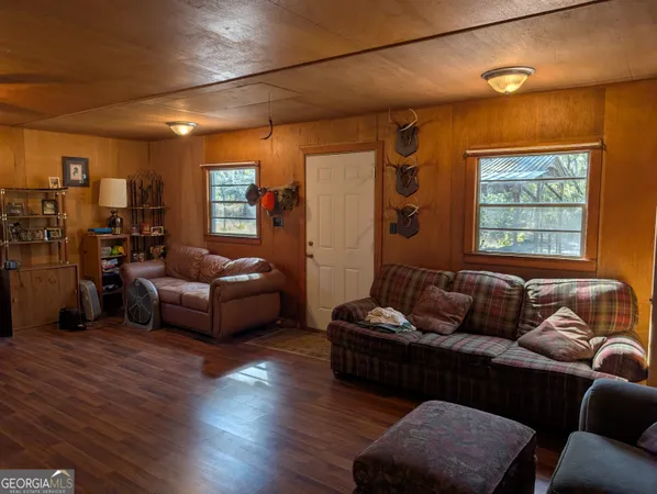 a living room with furniture and a dining table with wooden floor