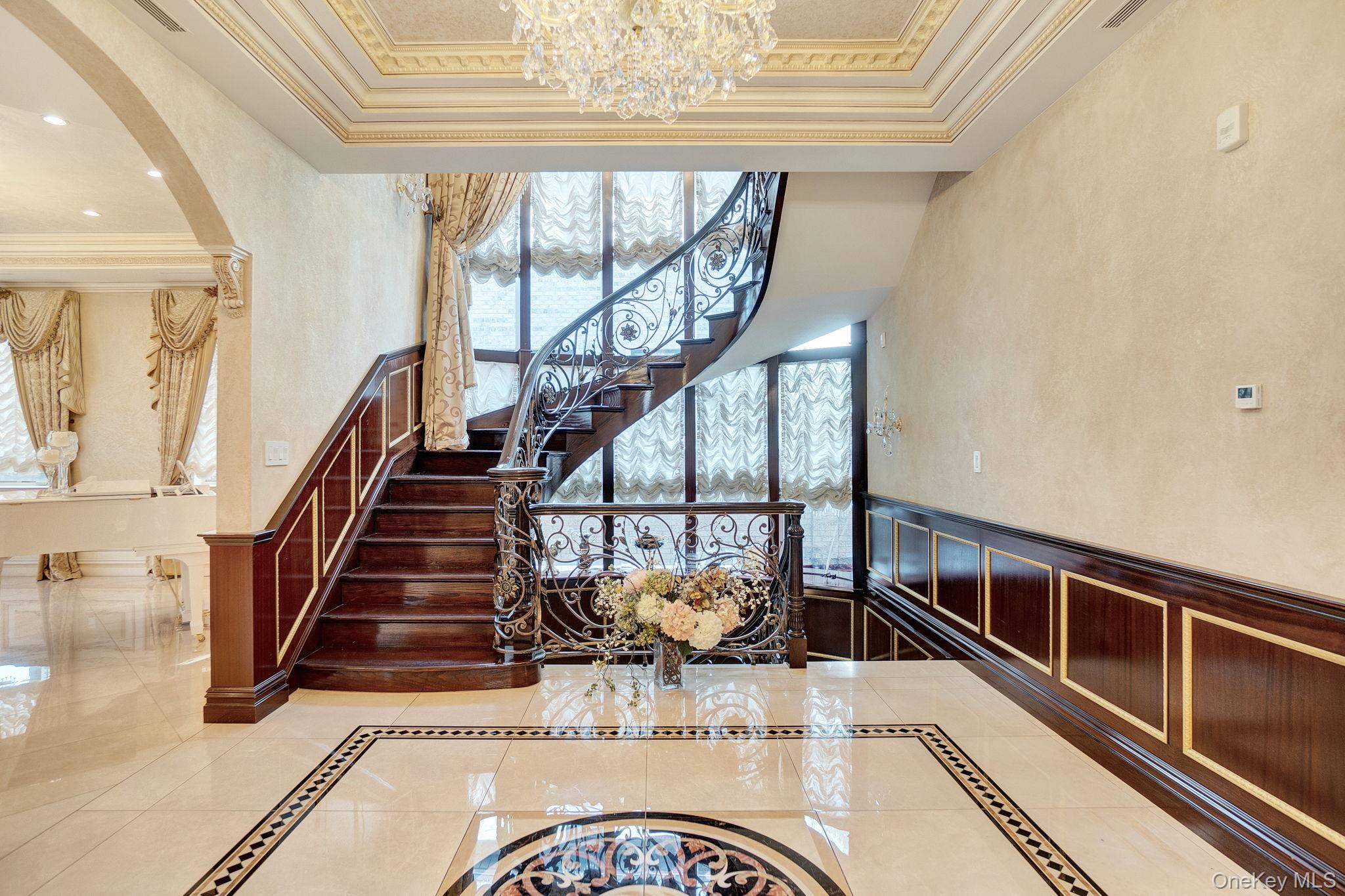 181-30 Tudor Road Queens, NY 11432 - Photo 5 of 46 Stairs with inlaid floor details, ornamental molding, arched walkways, a chandelier, and tile patterned floors