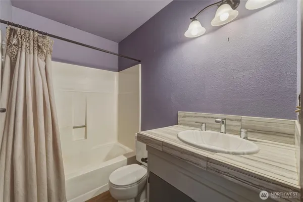 a bathroom with a granite countertop sink toilet and shower