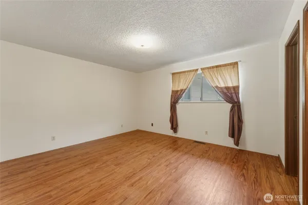 an empty room with wooden floor and cabinet