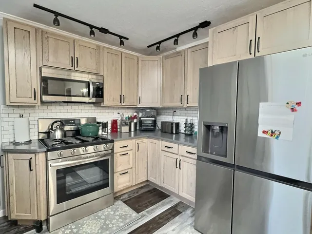 a kitchen with stainless steel appliances granite countertop white cabinets and refrigerator