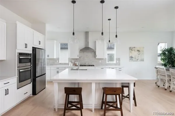 a kitchen with stainless steel appliances granite countertop a sink a stove a refrigerator and island with wooden floor