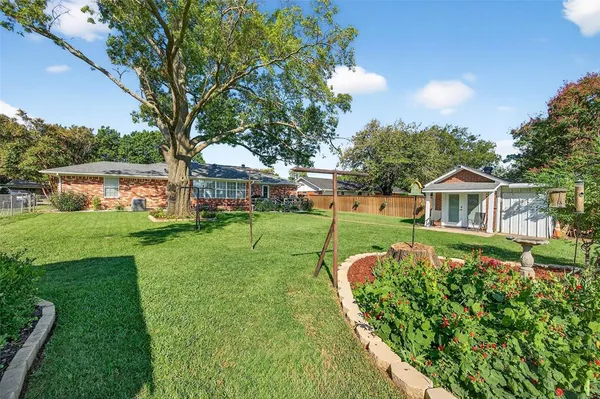 a view of a house with a big yard plants and large trees