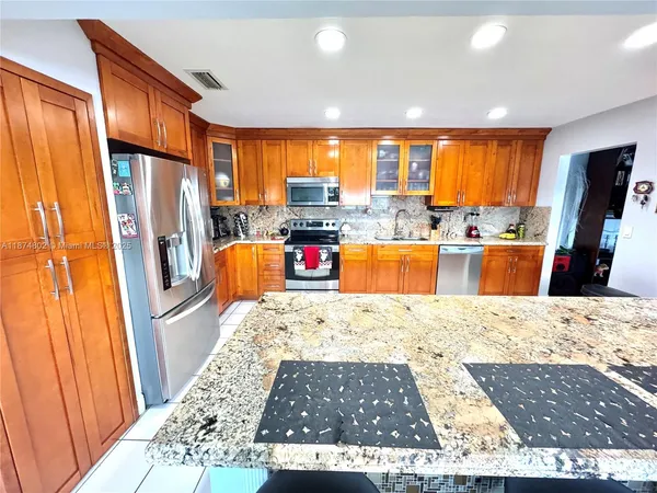 a kitchen with granite countertop a stove a sink and a refrigerator